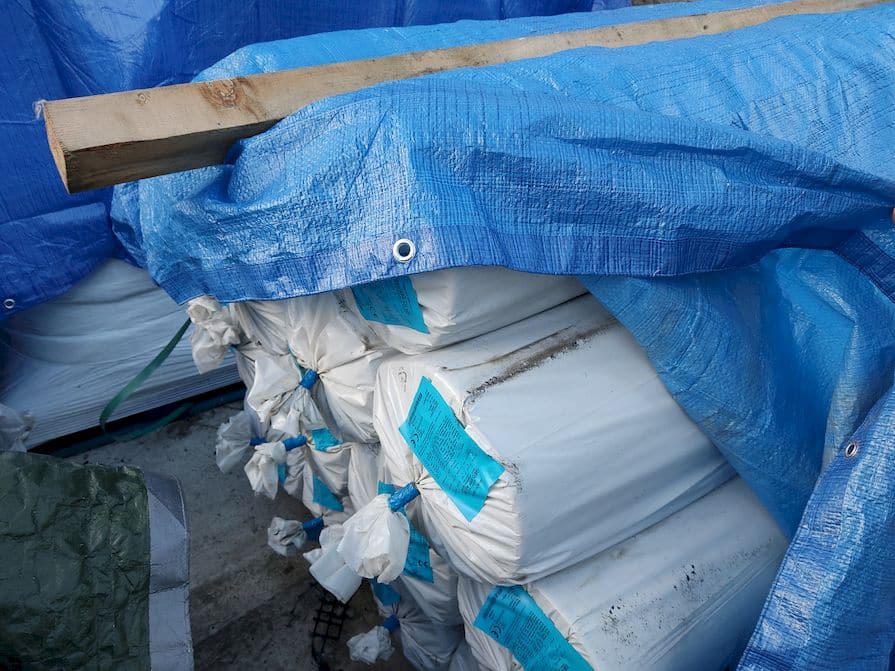 Stapel von Geotextilrollen, verpackt und unter einer blauen Plane aufbewahrt